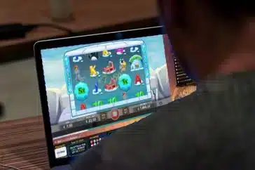 Istuu tietokoneen ääressä ja katsoo jotakuta, joka striimaa kun hän pelaa Kolikkopelejä online