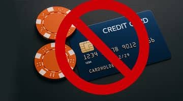 Ett blått kreditkort och två orange spelmarker ligger på ett mörkt bord. Ett rött förbudsmärke täcker kreditkortet och spelmarkerna för att symbolisera svenska regeringens lagförslag om totalt förbud mot spel med kredit.